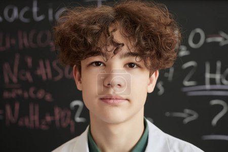 Téléchargez les photos : Portrait de l'adolescent en blouse de laboratoire en classe de sciences et regardant la caméra - en image libre de droit