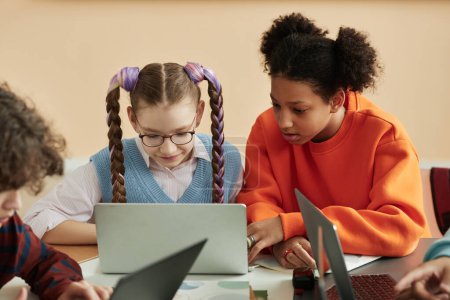 Téléchargez les photos : Portrait de deux écolières adolescentes utilisant un ordinateur portable ensemble en classe et étudiant ensemble - en image libre de droit