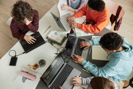 Foto de Vista superior en un grupo diverso de adolescentes escolares que usan computadoras en el aula que estudian juntos en la mesa - Imagen libre de derechos