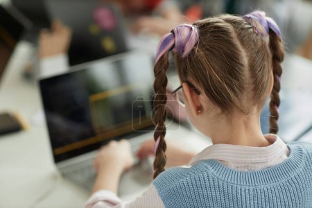Foto de Vista posterior en la colegiala con lindas coletas utilizando el ordenador portátil en la clase de programación de computadoras para niños, espacio de copia - Imagen libre de derechos