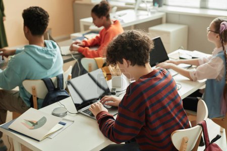 Foto de Vista de ángulo alto en el colegial adolescente usando el ordenador portátil en la clase de programación para los niños - Imagen libre de derechos