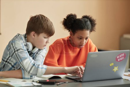 Téléchargez les photos : Garçon et fille utilisant un ordinateur portable en classe pendant la leçon de programmation - en image libre de droit
