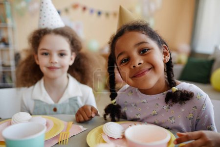 Téléchargez les photos : Portrait de deux filles heureuses regardant la caméra pendant la fête d'anniversaire et souriant - en image libre de droit