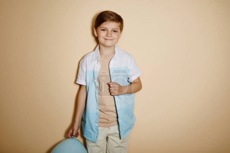 Foto de Retrato mínimo del niño sosteniendo el globo en la fiesta y sonriendo a la cámara contra fondo pastel con flash - Imagen libre de derechos