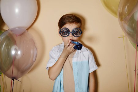 Foto de Cintura mínima hasta retrato del chico fiestero con globos en colores pastel disparados con flash. - Imagen libre de derechos