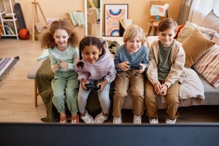Photo for High angle view at group of little children playing video games together and having fun - Royalty Free Image