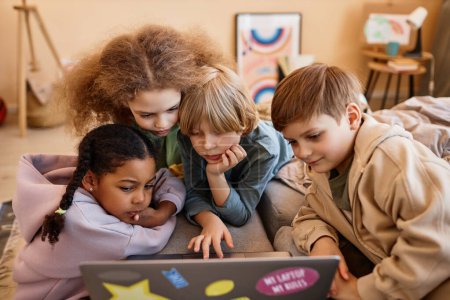Téléchargez les photos : Groupe d'enfants regardant l'écran d'ordinateur ensemble blotti sur l'ordinateur portable - en image libre de droit
