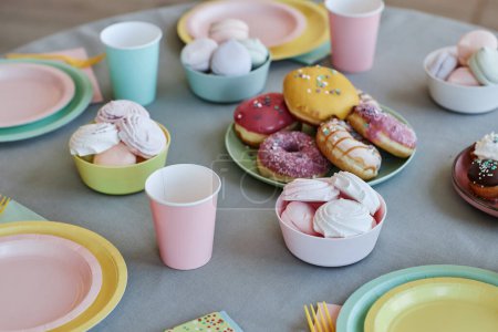 Téléchargez les photos : Image de fond de la table avec des bonbons et des beignets aux couleurs pastel à la fête des enfants, espace de copie - en image libre de droit