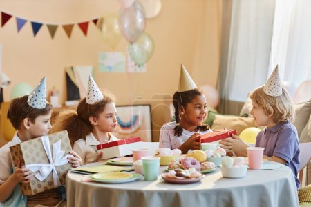 Photo for Diverse group of happy children opening presents at Birthday party - Royalty Free Image