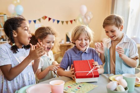 Foto de Diverso grupo de niños felices en la fiesta de cumpleaños con regalos de apertura niño emocionado - Imagen libre de derechos