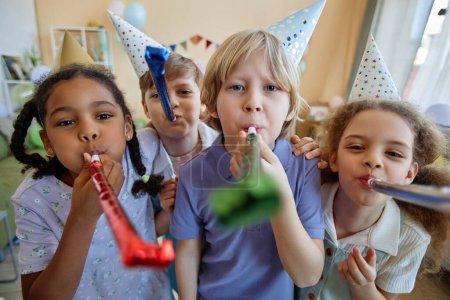 Téléchargez les photos : Vue de face portrait de trois enfants tenant des ventilateurs de fête et s'amusant à la célébration de l'anniversaire - en image libre de droit