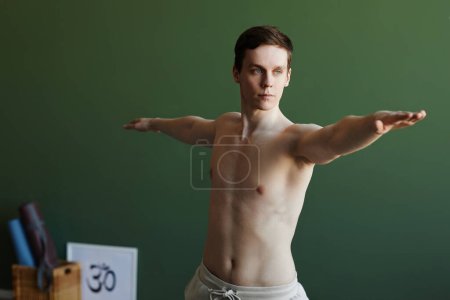 Foto de Cintura mínima hacia arriba retrato de un hombre sin camisa haciendo yoga contra el verde y mirando hacia otro lado, copiar espacio - Imagen libre de derechos