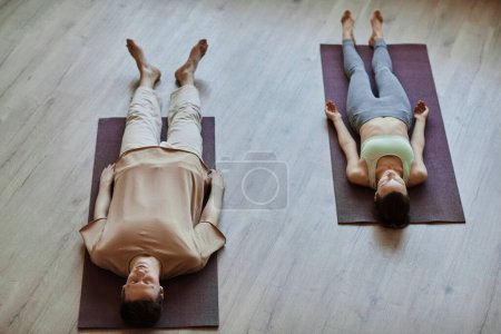 Photo for Top view at two young people lying down on floor in meditation with eyes closed, copy space - Royalty Free Image