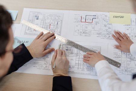 Téléchargez les photos : Vue de dessus deux ingénieurs mécaniciens au poste de travail dessinant les plans et les plans de l'avion - en image libre de droit