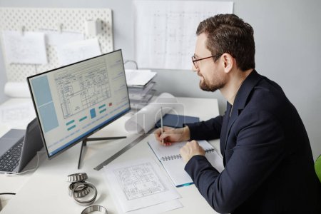 Téléchargez les photos : Portrait en grand angle d'un ingénieur barbu utilisant un ordinateur sur le lieu de travail et concevant des plans directeurs au bureau - en image libre de droit
