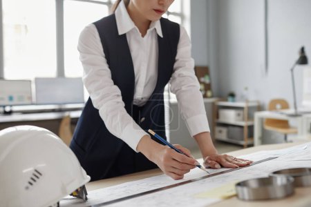 Photo for Closeup of female engineer drawing blueprints and plans at workstation in office, copy space - Royalty Free Image
