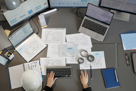 Photo for Wide angle top view at engineers workplace with blueprints and plans on computer desk, copy space - Royalty Free Image