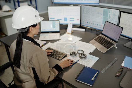Téléchargez les photos : Portrait en grand angle d'une ingénieure portant un casque de sécurité au travail au bureau et utilisant plusieurs ordinateurs, espace de copie - en image libre de droit