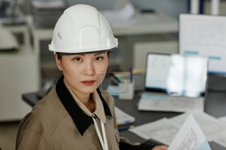 Téléchargez les photos : Gros plan portrait de femme asiatique portant un casque de sécurité sur le lieu de travail au bureau et regardant la caméra, l'espace de copie - en image libre de droit