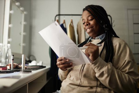 Foto de Retrato de una mujer afroamericana sonriente ensayando líneas en el vestidor mientras se prepara para el espacio de copia de rendimiento - Imagen libre de derechos