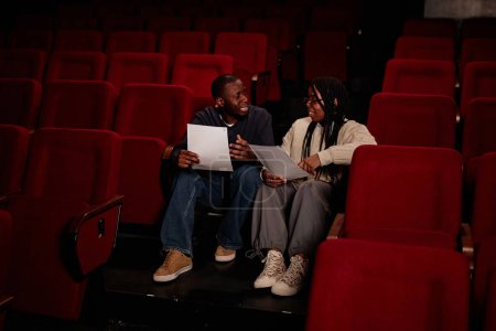 Foto de Retrato de larga duración de dos artistas afroamericanos sentados en el suelo en audiencia en el teatro y preparándose para el espacio de copia del espectáculo - Imagen libre de derechos