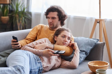 Photo for Portrait of young couple enjoying time together at home and cuddling on sofa, copy space - Royalty Free Image