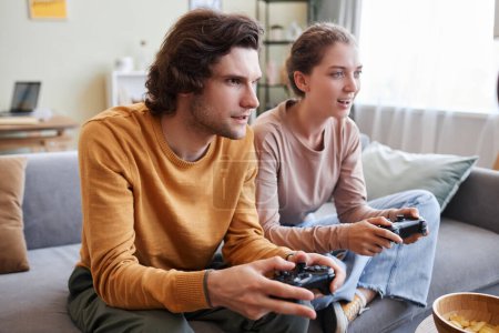 Téléchargez les photos : Jeune couple jouant ensemble à des jeux vidéo et tenant des contrôleurs - en image libre de droit