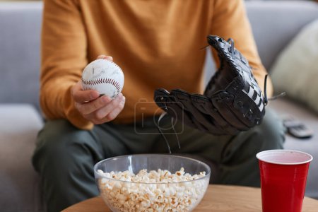 Foto de Primer plano del joven con guante de béisbol viendo partidos deportivos en casa, espacio para copiar - Imagen libre de derechos
