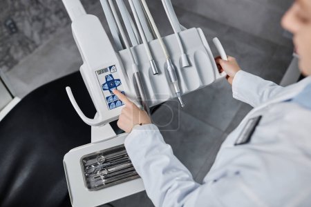 Téléchargez les photos : Gros plan sur le dentiste féminin installant son équipement dans une clinique dentaire moderne, espace de copie - en image libre de droit