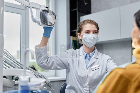 Photo for Portrait of young woman as female dentist wearing mask preparing for examination in dental clinic - Royalty Free Image