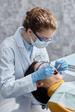 Photo for Vertical portrait of female dentist wearing mask during examination in dental clinic - Royalty Free Image