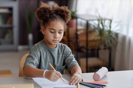 Téléchargez les photos : Portrait de petite fille noire avec de jolies photos de coiffure de pain à la maison à l'aide de crayons de couleur - en image libre de droit