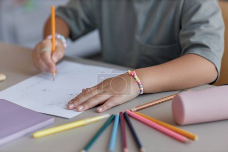 Foto de Primer plano de la cara de dibujo niña con lápices de colores en la mesa en el interior, espacio de copia - Imagen libre de derechos
