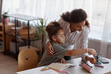 Photo for Side view portrait of caring black mother helping little girl drawing pictures at home - Royalty Free Image