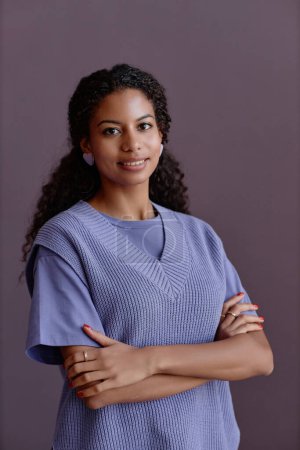 Téléchargez les photos : Portrait taille haute minime de jeune femme noire franche souriant à la caméra portant une tenue violette - en image libre de droit