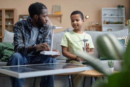 Foto de Retrato del padre afroamericano enseñando a su hijo sobre fuentes de energía renovables y sosteniendo el modelo de turbina eólica - Imagen libre de derechos