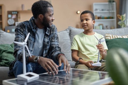 Foto de Retrato del padre afroamericano enseñando a su hijo sobre fuentes de energía renovables y paneles solares - Imagen libre de derechos