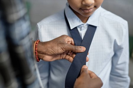 Gros plan du père attentionné méconnaissable enseignant fils attacher cravate tout en s'habillant de vêtements de formalerie