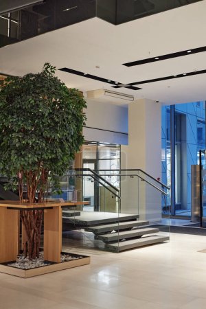 Foto de Imagen de fondo vertical del vestíbulo del hotel o del interior del edificio de oficinas con escalera y decoración de árboles verdes - Imagen libre de derechos
