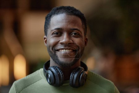 Photo for Front view portrait of African American young man with headphones smiling at camera blurred background copy space - Royalty Free Image