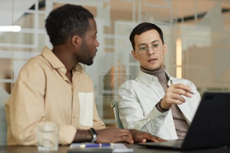 Photo for Minimal portrait of successful business people discussing project in meeting and pointing at laptop screen - Royalty Free Image