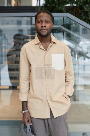 Photo for Vertical portrait of young African American man looking at camera posing in office building - Royalty Free Image