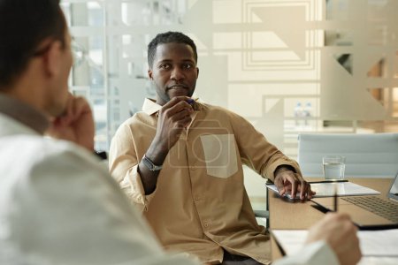 Photo for Minimal portrait of successful Black man discussing project with colleague during work meeting in designer office copy space - Royalty Free Image