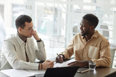 Photo for Minimal portrait of two male business people working on project in meeting and taking notes - Royalty Free Image