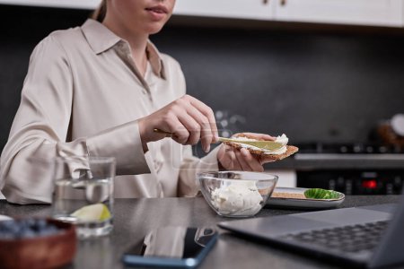 Téléchargez les photos : Gros plan de la jeune femme profitant d'un petit déjeuner sain le matin et regardant l'écran d'ordinateur portable, copier l'espace - en image libre de droit