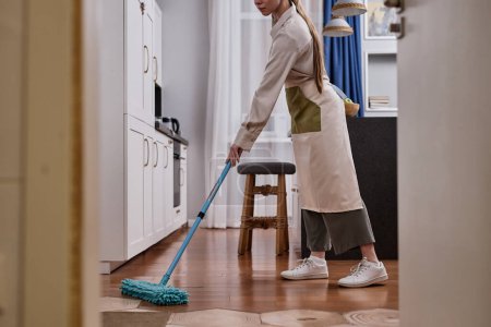 Téléchargez les photos : Vue latérale de la jeune femme qui nettoie les planchers et l'appartement de nettoyage le week-end, espace de copie - en image libre de droit