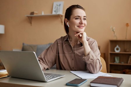 Photo for Portrait of smiling businesswoman working from home and looking at window pensively, copy space - Royalty Free Image