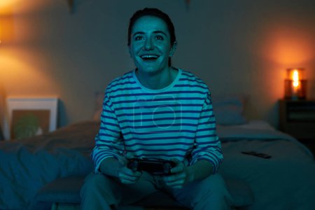 Foto de Retrato de vista frontal de la joven emocionada jugando videojuegos en la oscuridad, espacio de copia - Imagen libre de derechos