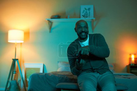 Foto de Retrato de hombre negro adulto emocional jugando videojuegos en la oscuridad en casa, espacio de copia - Imagen libre de derechos