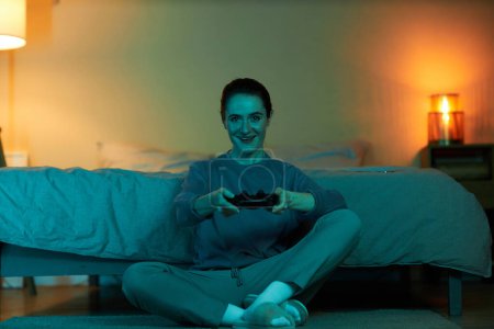 Téléchargez les photos : Portrait complet d'une femme adulte jouant à des jeux vidéo dans l'obscurité et tenant le contrôleur, espace de copie - en image libre de droit